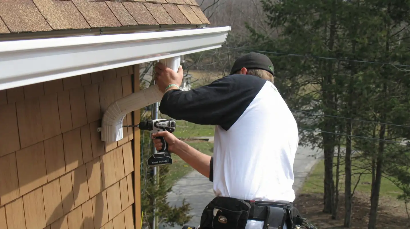 Professional contractor installing tan vinyl siding panels on a residential home exterior in Rockford, IL